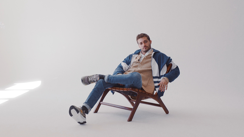 male model in casula cloth sitting on chair looking into the camera