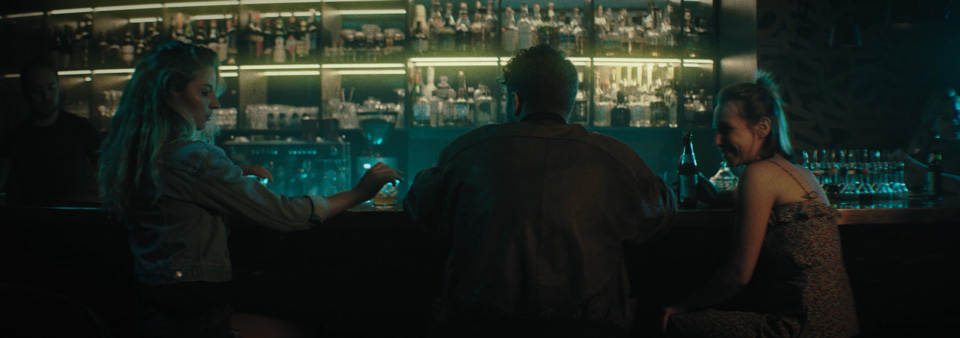 a man is sitting at a bar with a woman to his left and a woman to his right