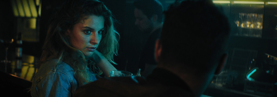 a woman and a man sitting at a bar, the woman is looking at the man