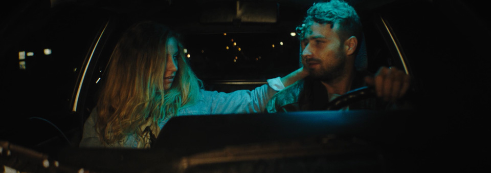 a woman and a man sitting in a car, the woman strokes the man's hair