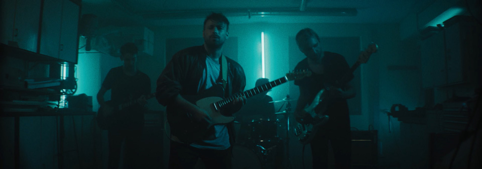a rock band is performing in a dark basement with guitarist in front